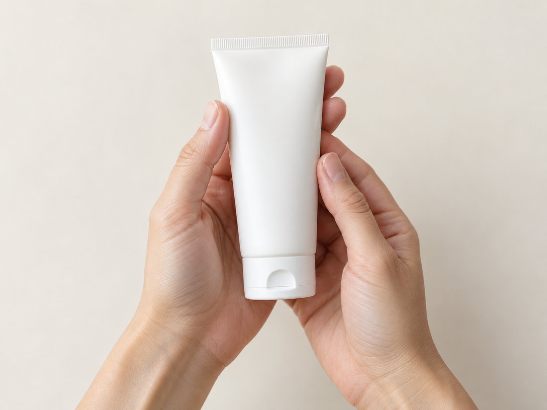 Hands holding a white tube of hand cream