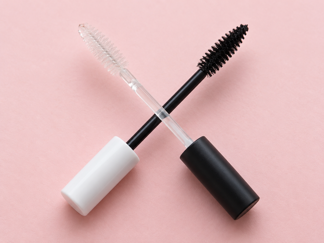 Clear mascara primer wand crossed with a black mascara wand